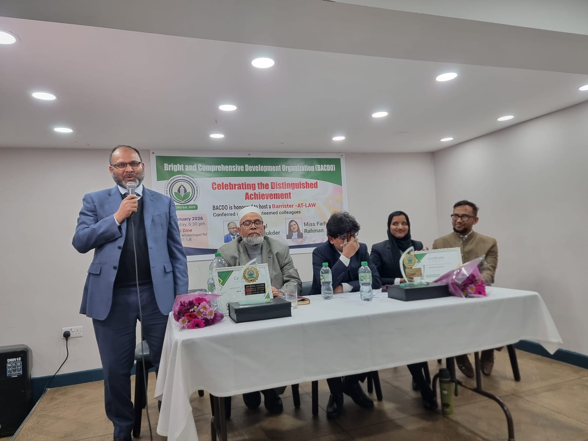 সংবাদ ব্রিফিংয়ে মাইক্রোফোনে বক্তব্য, পাশে সংগঠনের প্যানেল